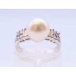 An 18 ct white gold and pearl ring flanked by baguette cut and round diamonds. Ring size I.