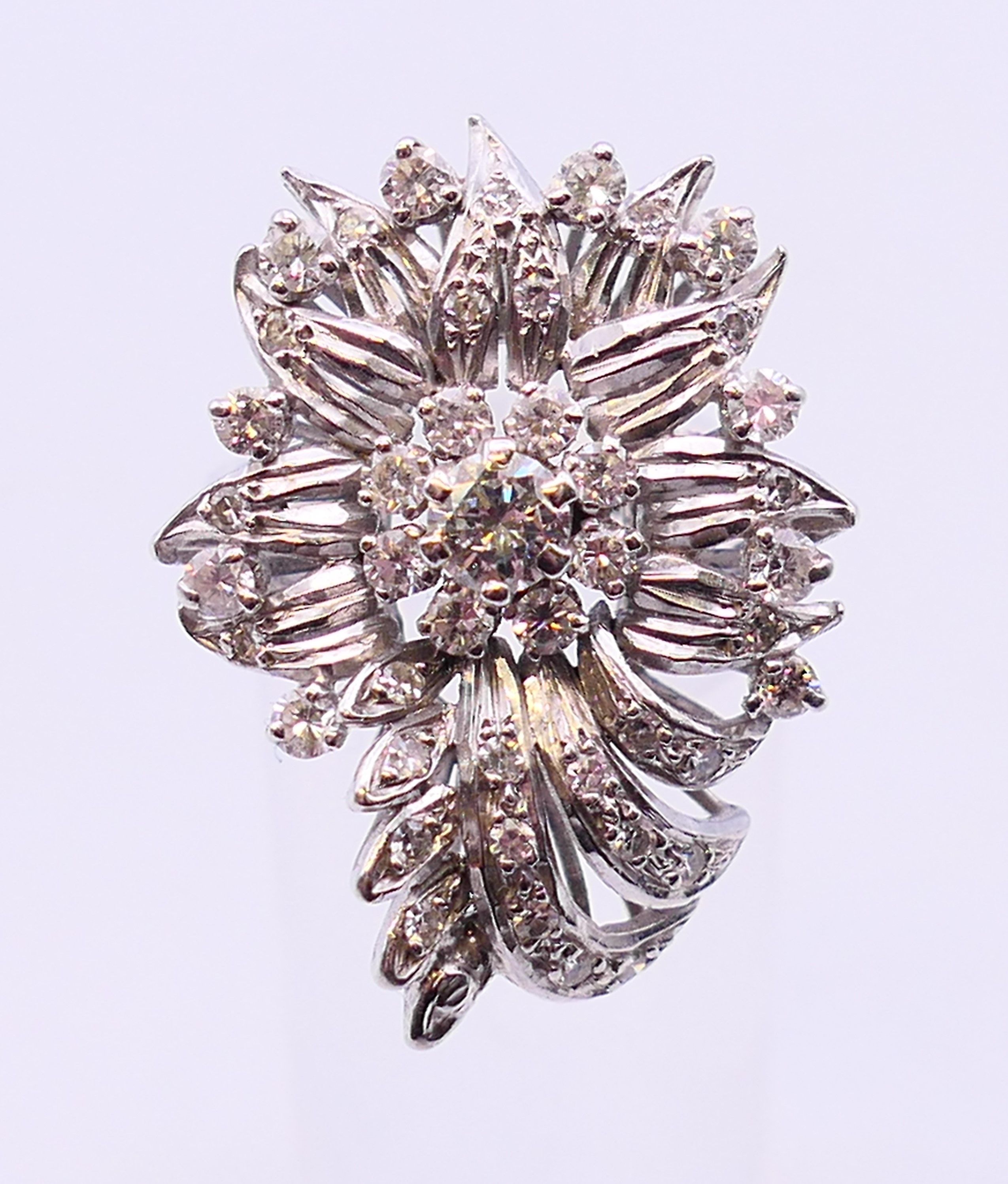 An unmarked platinum or white gold, diamond floral spray ring. 3cms long. Ring size Q/R.