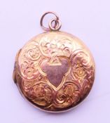 An antique 9 ct gold back and front engraved locket. 2.5 cm diameter.
