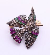 An unmarked bird brooch set with rubies, emeralds and diamonds. 2.5 cm wide. 5.1 grammes.