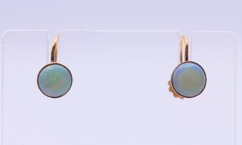 A pair of 9 ct gold and opal earrings. Each 6 mm diameter.