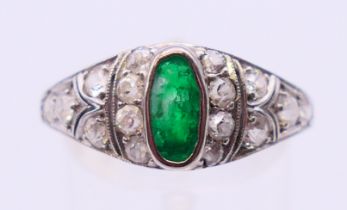 An unmarked platinum, emerald and diamond ring. Ring size T.