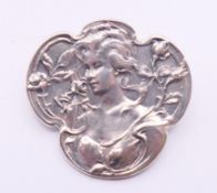 A silver Art Nouveau-style brooch decorated with a girl. 3.5 cm wide.