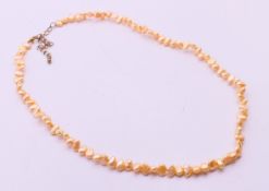 A peach-coloured freshwater pearl necklace. 42 cm long.