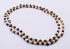 A tiger's eye and pearl bead necklace. 118 cm long.
