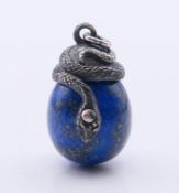 A silver and lapis lazuli snake and egg pendant. 3 cm high.