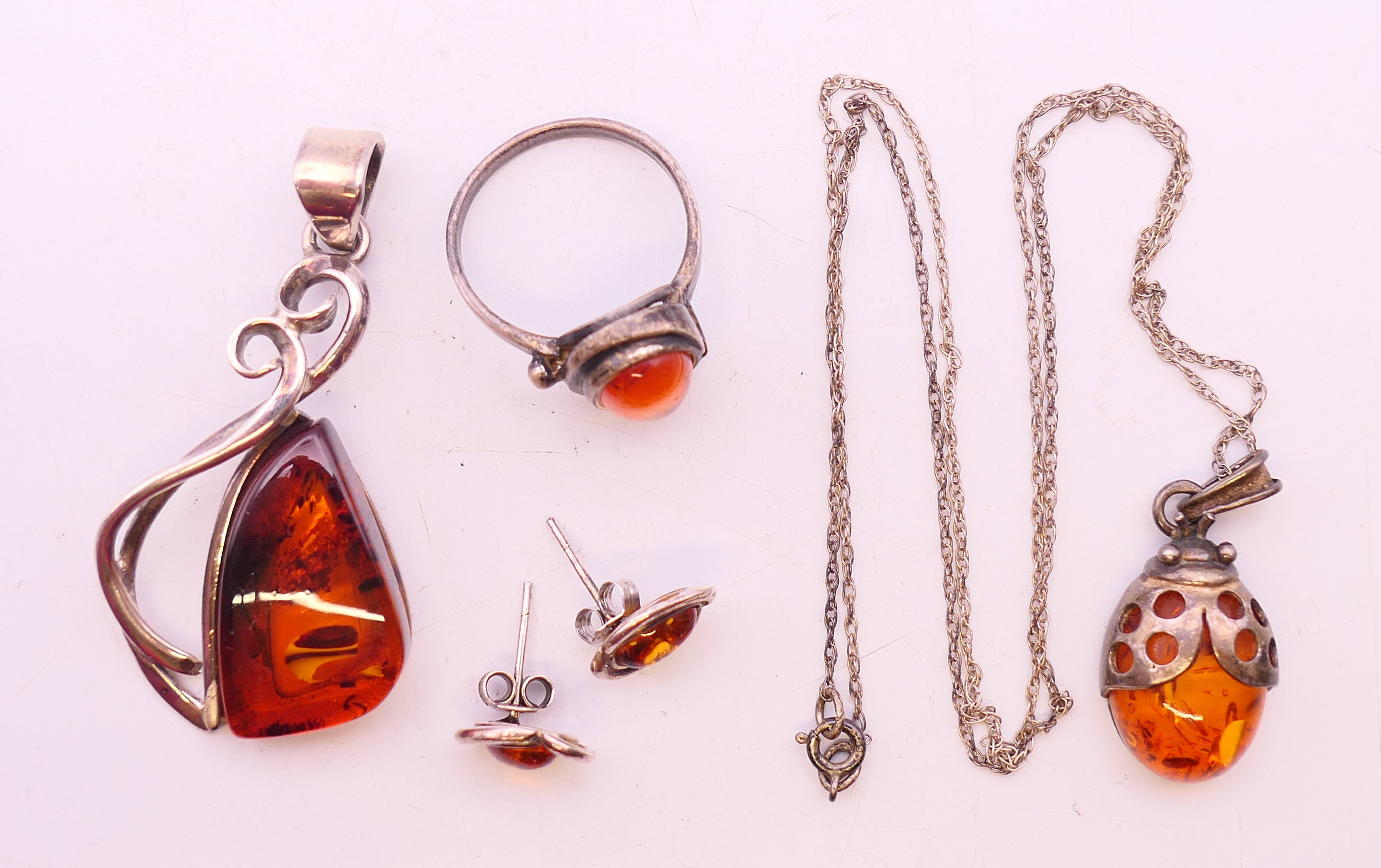 Four silver and amber items of jewellery. The largest pendant 5 cm high.