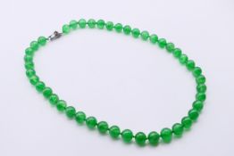 A jade bead necklace with a diamond set snake form clasp. 60 cm long.