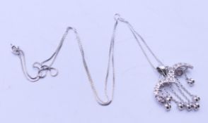 A 14 K white gold and diamond falling heart pendant on a 14 K white gold chain.