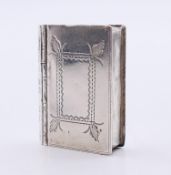 A silver pill box in the shape of a book. 3 cm high.