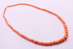 A vintage Chinese carved coral bead necklace with unmarked gold clasp. 75 cm long.