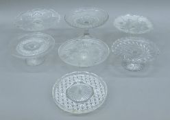 Seven glass pedestal cake dishes. The largest 15 cm high.