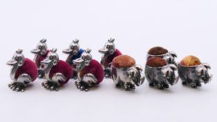 A quantity of pin cushions in the form of ducks and pigs and a pair of silver earrings.
