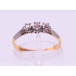 An 18 ct gold and platinum three-stone diamond ring. Ring size M.