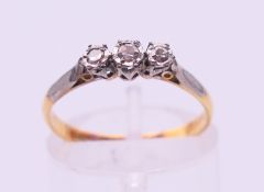 An 18 ct gold and platinum three-stone diamond ring. Ring size M.