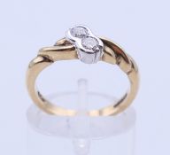 A 9 ct gold two-stone diamond crossover ring. Ring size K/L.