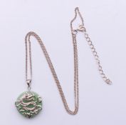 A silver dragon motif and jade pendant on a silver chain. Pendant 2 cm diameter, chain 44 cm long.