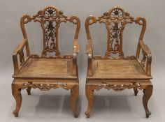 A pair of Chinese carved hardwood open armchairs. Each 57 cm wide.