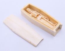 A bone miniature coffin with skeleton. 11.5 cm long.