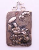 A 19th century Japanese pendant/plaque depicting figures in a storm, worked in gold,