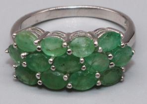 Silver cluster ring set with thirteen oval cut emeralds in claw settings, on plain shank, stamped