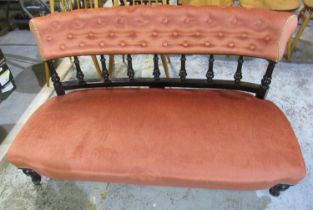 Victorian ebonized framed couch, deep buttoned and pierced back rail on brass sockets with castors