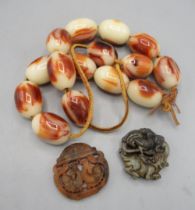 Red jade pendant with two carp in bowl, a green jade pendant with elephant and peacock design, and a