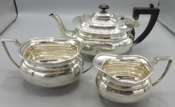 George V Art Deco silver matched three piece tea service, teapot with ebonised handle and final,