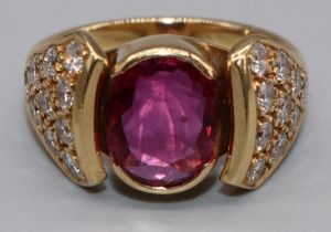 18ct yellow gold diamond and ruby ring by Susan Wright, the central oval cut ruby in split bezel