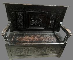 17th century style ebonised oak box settle, with figural and scroll carved panel back, mask head