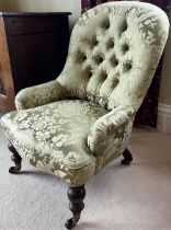 Victorian nursing chair, buttoned back, low arms and serpentine seat on turned supports, brass