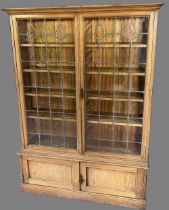 Edwardian golden oak bookcase, moulded cornice above a pair of lead glazed doors enclosing four