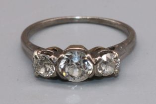 White metal three stone diamond ring, the central round cut diamond in split bezel setting,