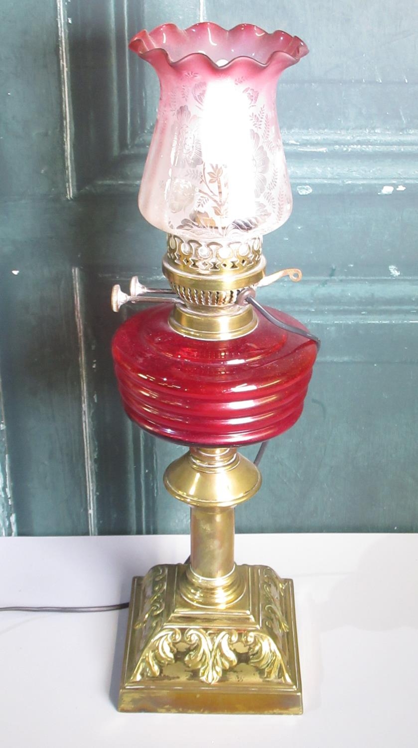 20th century brass oil lamp, with red glass reservoir and cranberry tint etched shade, now converted