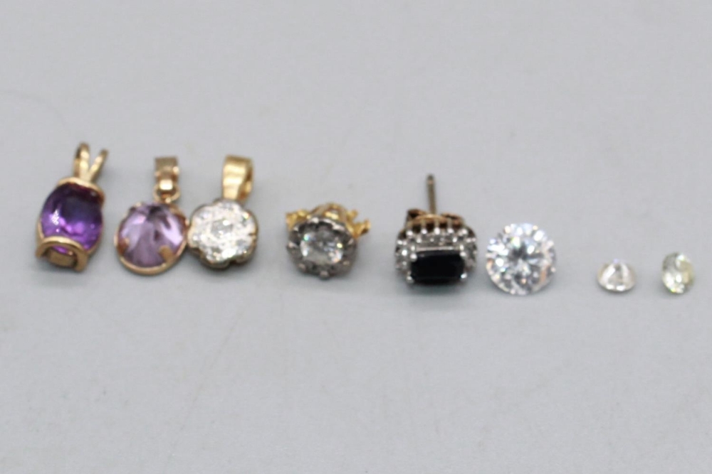 Two small unmounted diamonds, a larger clear stone, a yellow and white metal cluster drop pendant, a