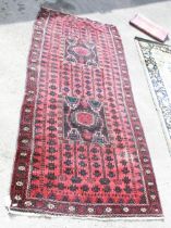 C20th Caucasian rug, red field with two square medallions, red geometric repeating pattern border,