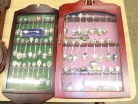 Collection of EPNS souvenir spoons in two glazed cabinets and C20th mahogany aneroid wheel