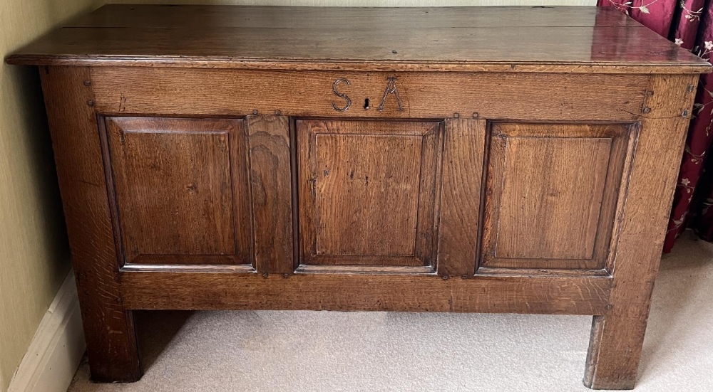 George III oak coffer, hinged plank top with moulded edge above four fielded panel front, carved