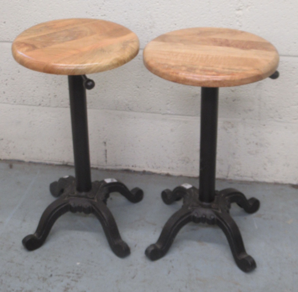 C20th pair of cast iron machinist type stools with circular beech height adjustable seats, minimum