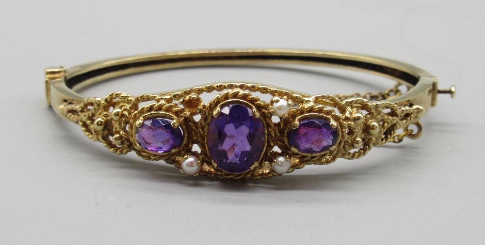 9ct yellow gold hinged bangle, with ornate pierced font set with purple stones and seed pearls (1