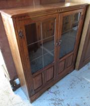 Reproduction oak bookcase with two part glazed panel doors and adjustable shelves on bracket feet,