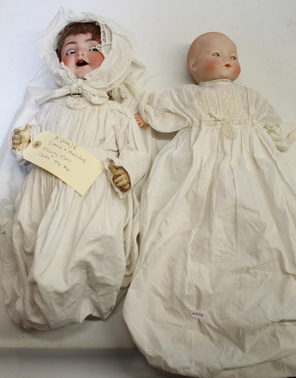 Two early 20th century bisque head baby dolls: crying doll marked Simon and Halbig 126, white gown
