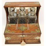 Late 19th century oak three bottle tantalus, metal mounts, twin lidded compartment, with key and