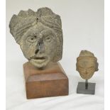 Two carved stone heads on wood and stone plinths, origins unknown, larger carving with plinth