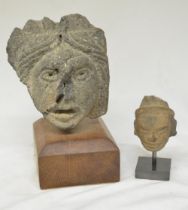 Two carved stone heads on wood and stone plinths, origins unknown, larger carving with plinth