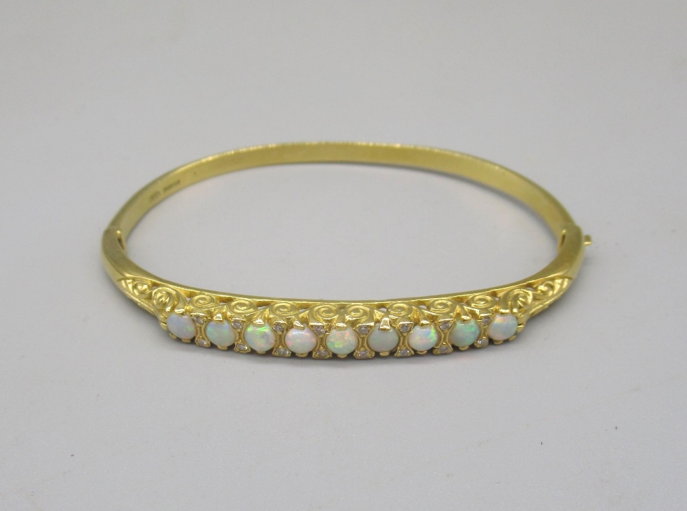 18ct yellow bangle set with nine opals between brilliant cut diamonds on scroll mount, stamped