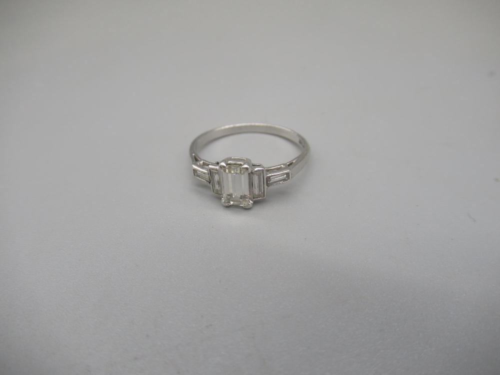 Platinum ring set with central emerald cut diamond, flanked by two baguette cut diamonds, stamped