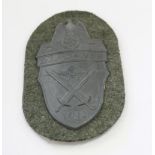 German Demjansk Shield with field grey cloth backing, backing paper and four pins intact.