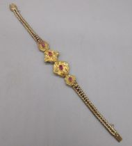 Unmarked yellow gold bracelet with ruby and diamond set panels on articulated chain, tested to