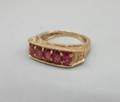 14ct rose gold ring set with five oval cut red sapphires in ornate mount, size N, stamped 14k, 4.9g